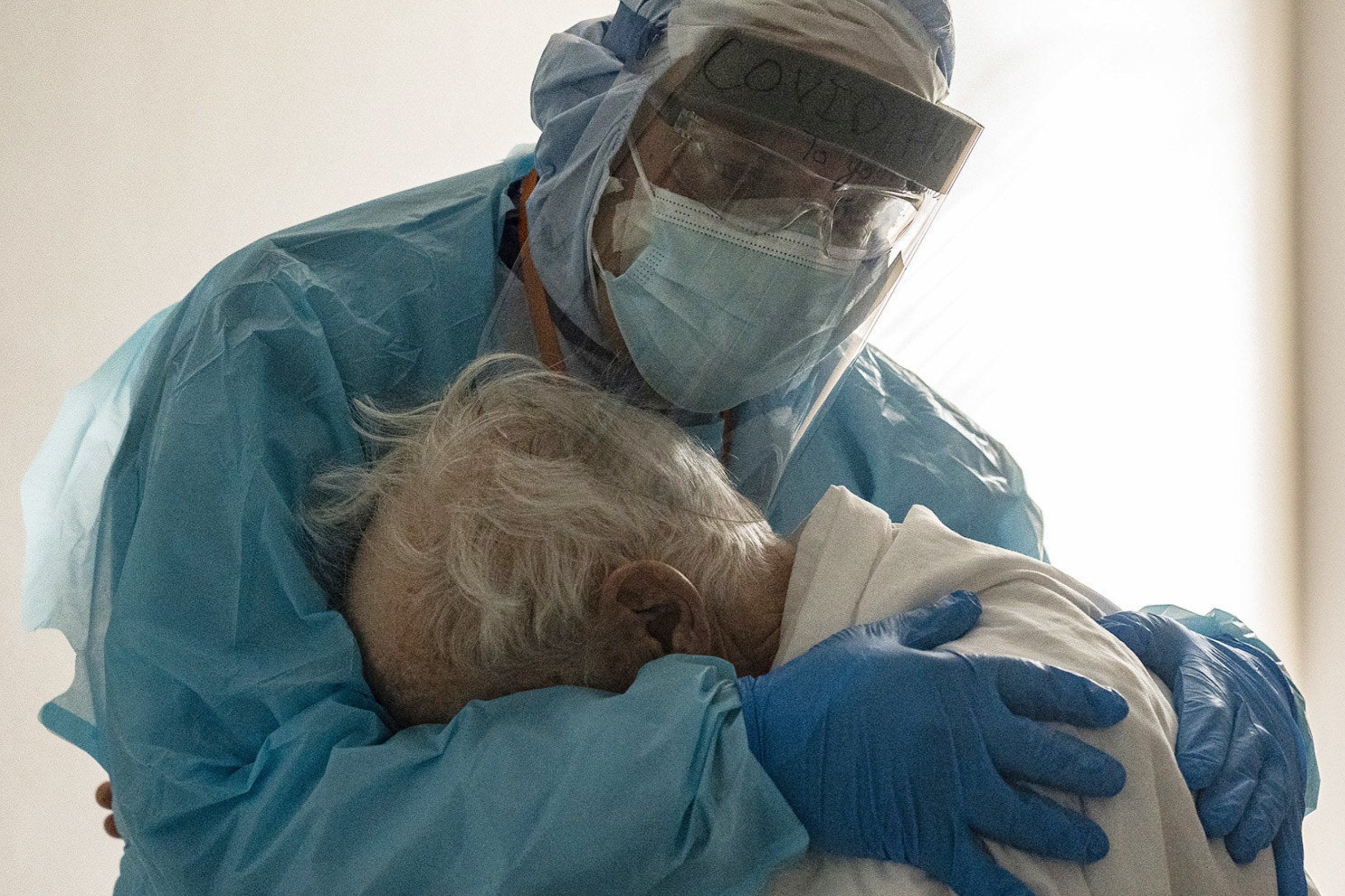 a doctor in full PPE holds a patient