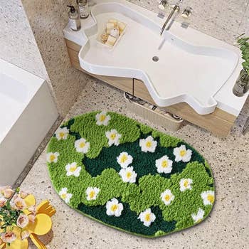 Oval-shaped bathroom rug with green and white floral design placed near a uniquely shaped sink