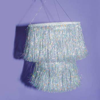 Hanging tinsel fringe chandelier with a shimmering, layered design on a plain background