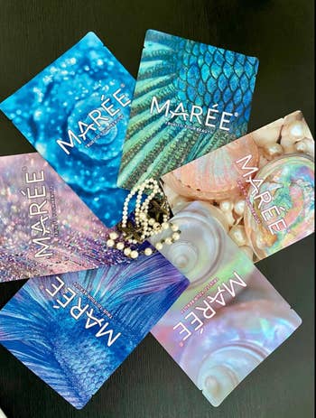 Assorted Maree beauty product packages with ocean-inspired textures and designs, arranged in a fan shape on a table