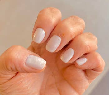 Close-up of a hand displaying neatly manicured nails with a glossy finish, suitable for a style or beauty shopping article