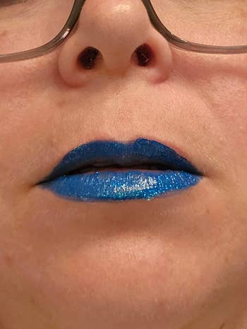 Close-up of a person wearing bold, shimmering blue lipstick