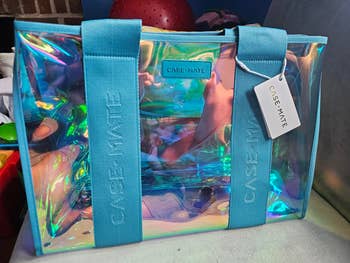 Iridescent tote bag with aqua straps and a CASE•MATE logo label, ideal for stylish shopping. Tag attached