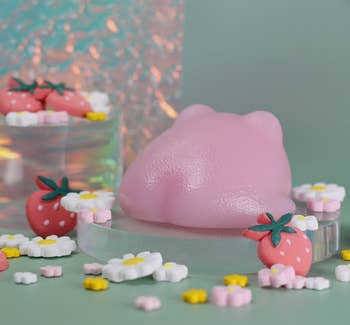 Pink bear-shaped soap amidst decorative strawberries and daisies