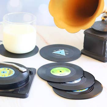 Vinyl record coasters and a glass of milk are displayed next to a vintage gramophone