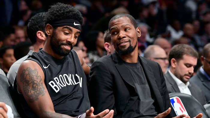 Kyrie Irving #11 and Kevin Durant #7 of the Brooklyn Nets speak on the bench.