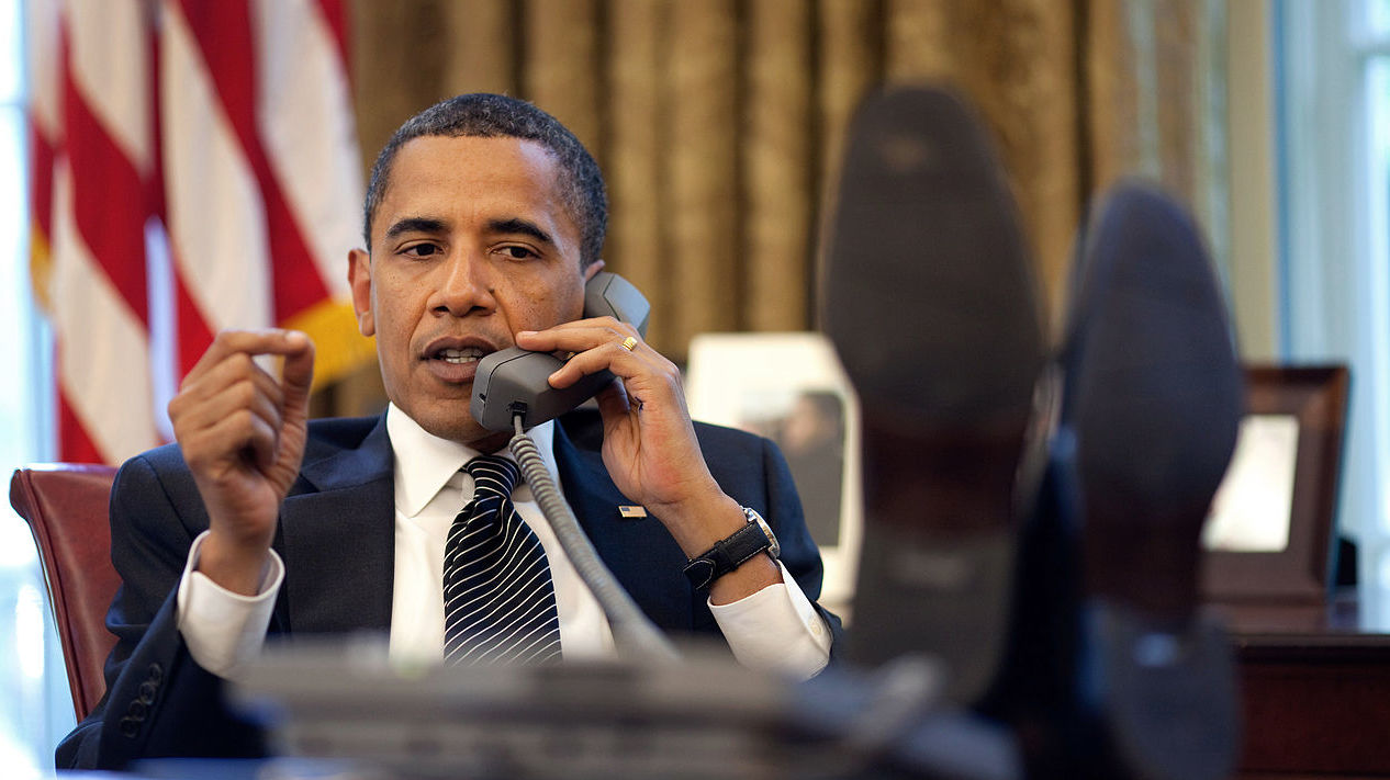 Obama talks on the phone at his desk.
