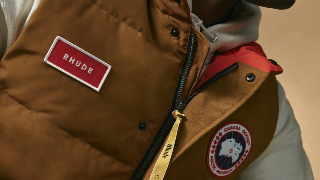 A brown vest worn by a model, with the Canada Goose and RHUDE logos visible
