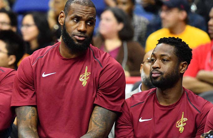 Dwyane Wade and LeBron James sit on the bench.