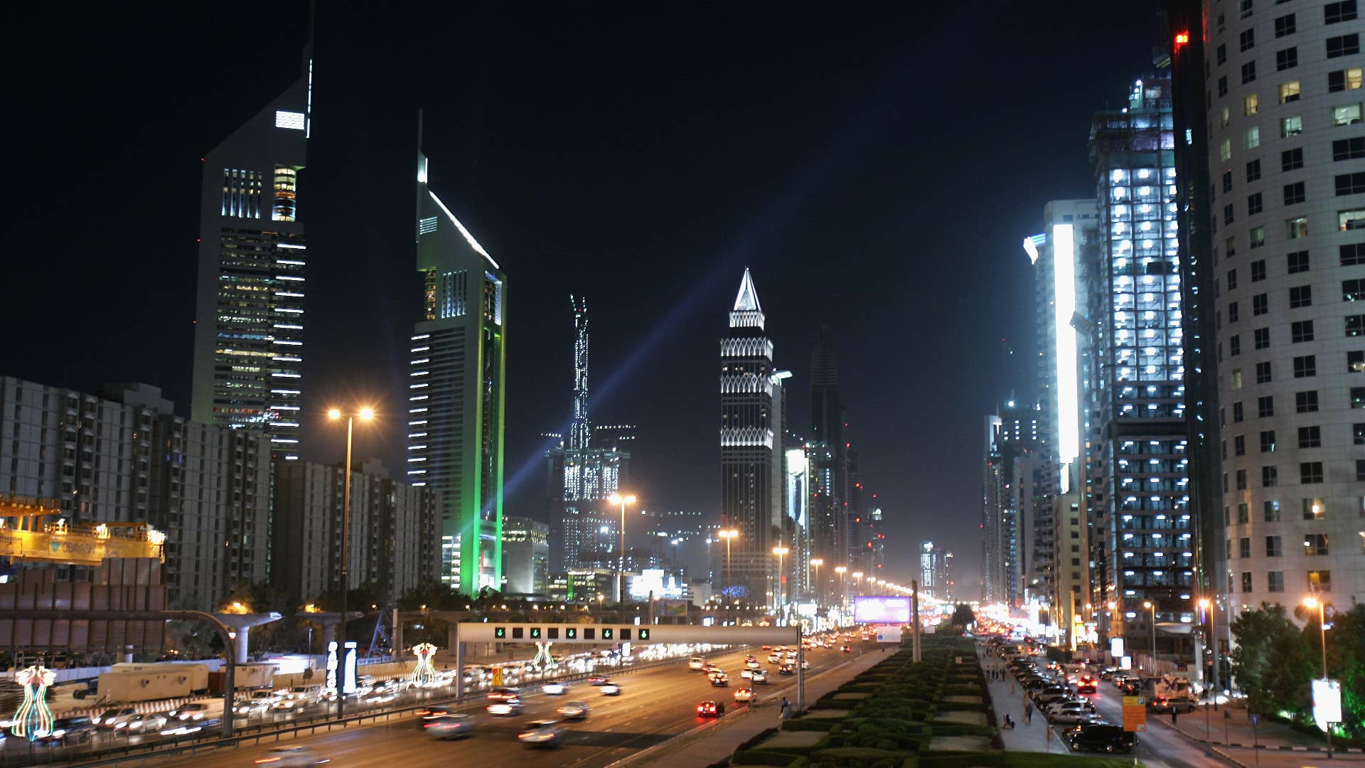 The iconic Emirates Towers dominate the skyline beside the wide boulevard of Sheikh Zayed Road.