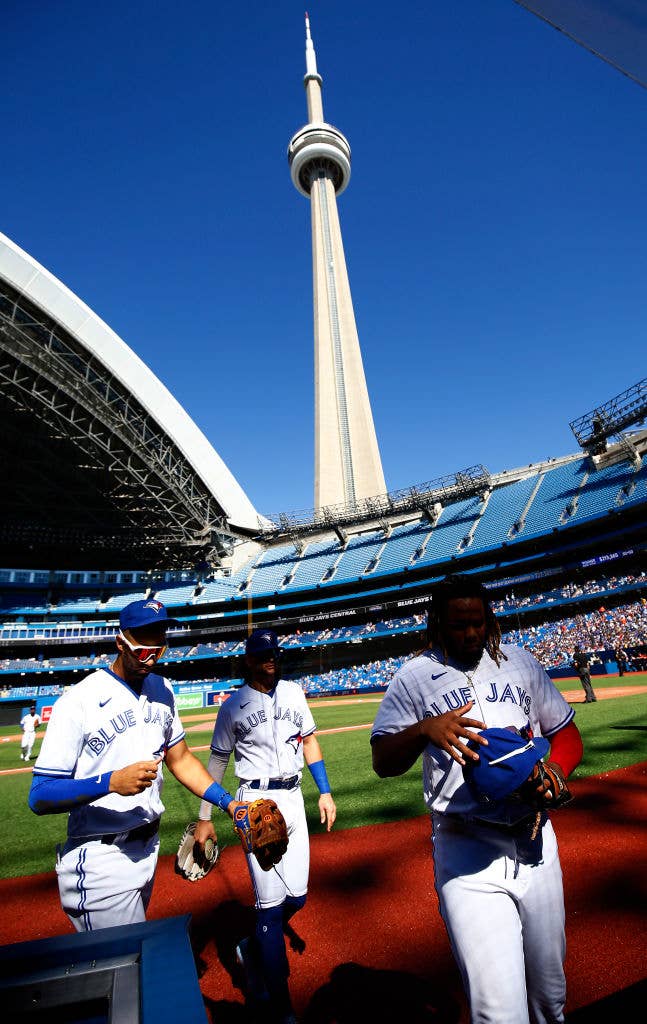 Vlad Guerrero Jr., Lourdes Gurriel Jr., and Bo Bichette walking to the dugout of the Rogers Centre.