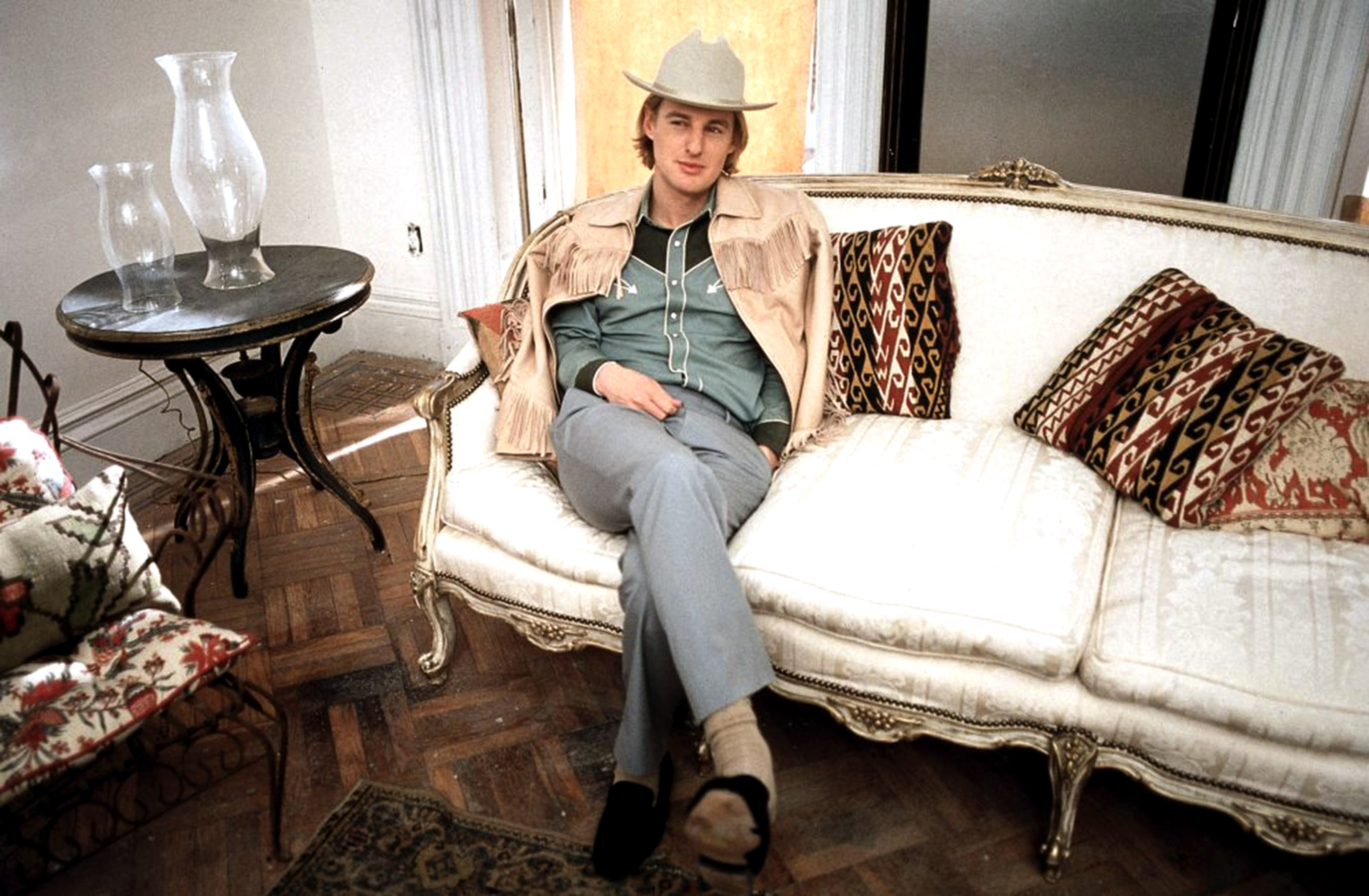 Owen Wilson in a cowboy hat on the couch.