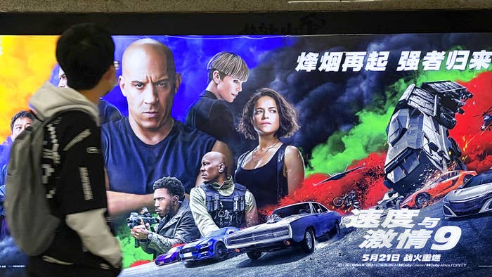 A man walks past a poster for 'F9'.