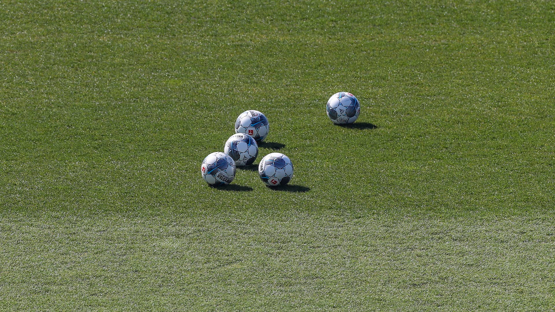 Five balls are lying on the grass of FC Schalke's training facility