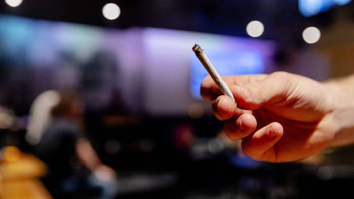 This photograph shows person holding a lit cannabis &quot;joint&quot; in Cremers Coffee Shop in The Hague.