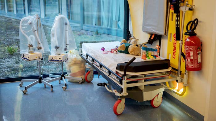 A bed adorned with plush toys is displayed in a hallway at the pediatric polyclinic emergency unit