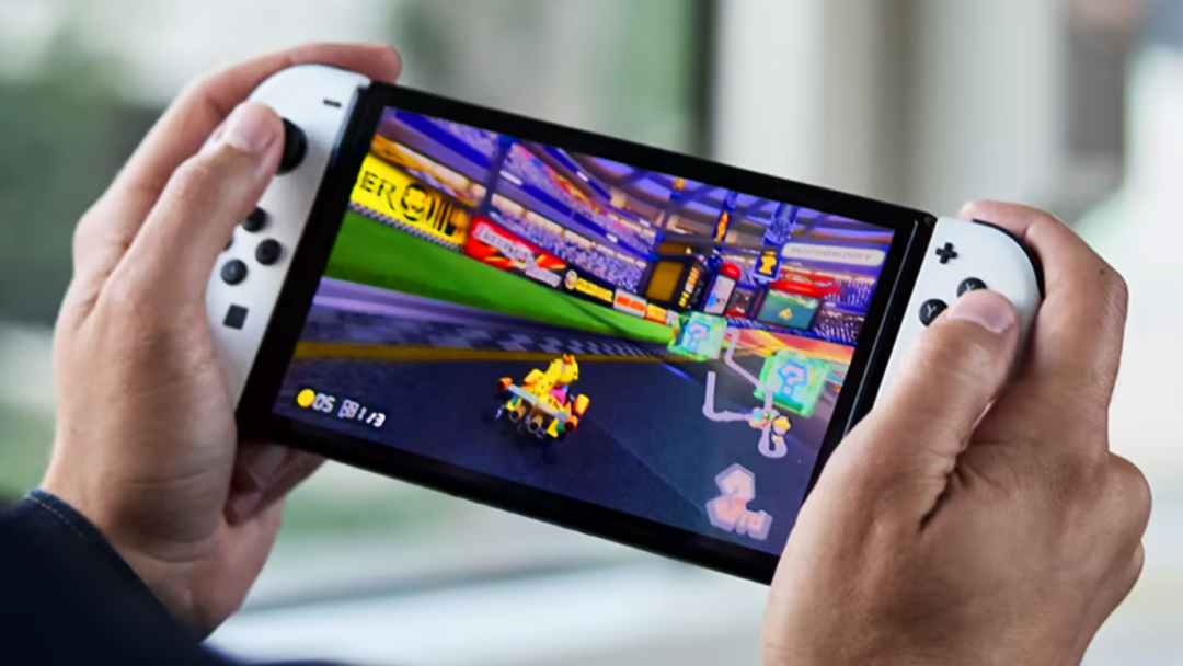 Close up photo of hands holding a Nintendo Switch OLED as they play Mario Kart.