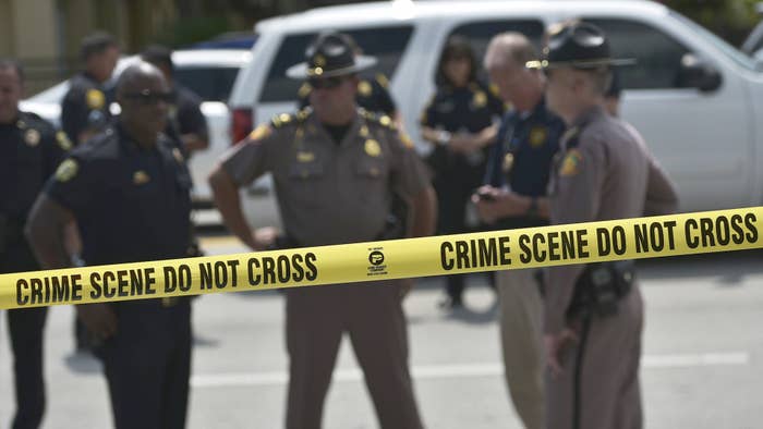 Police stand behind a crime scene tape