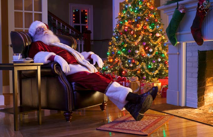 Santa sleeping in chair next to tree