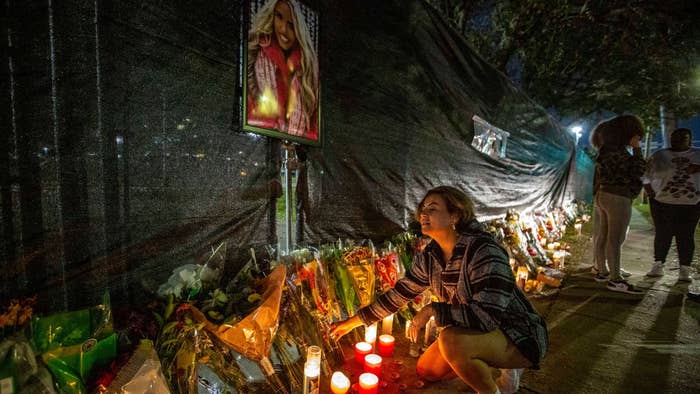 A woman seen kneeling by candles outside NRG Park