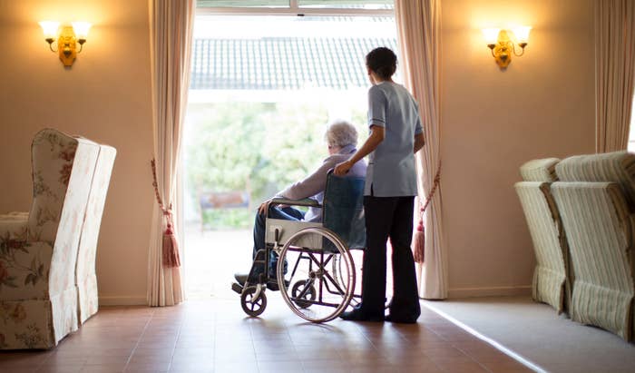 Nurse pushing patient in wheelchair at nursing home