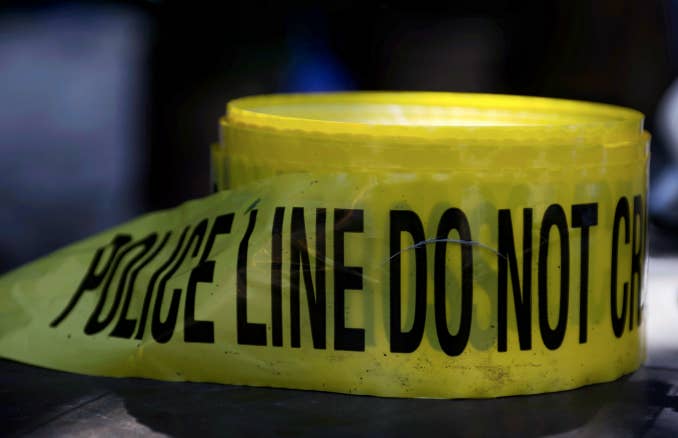 Roll of crime scene tape is unused as police officers