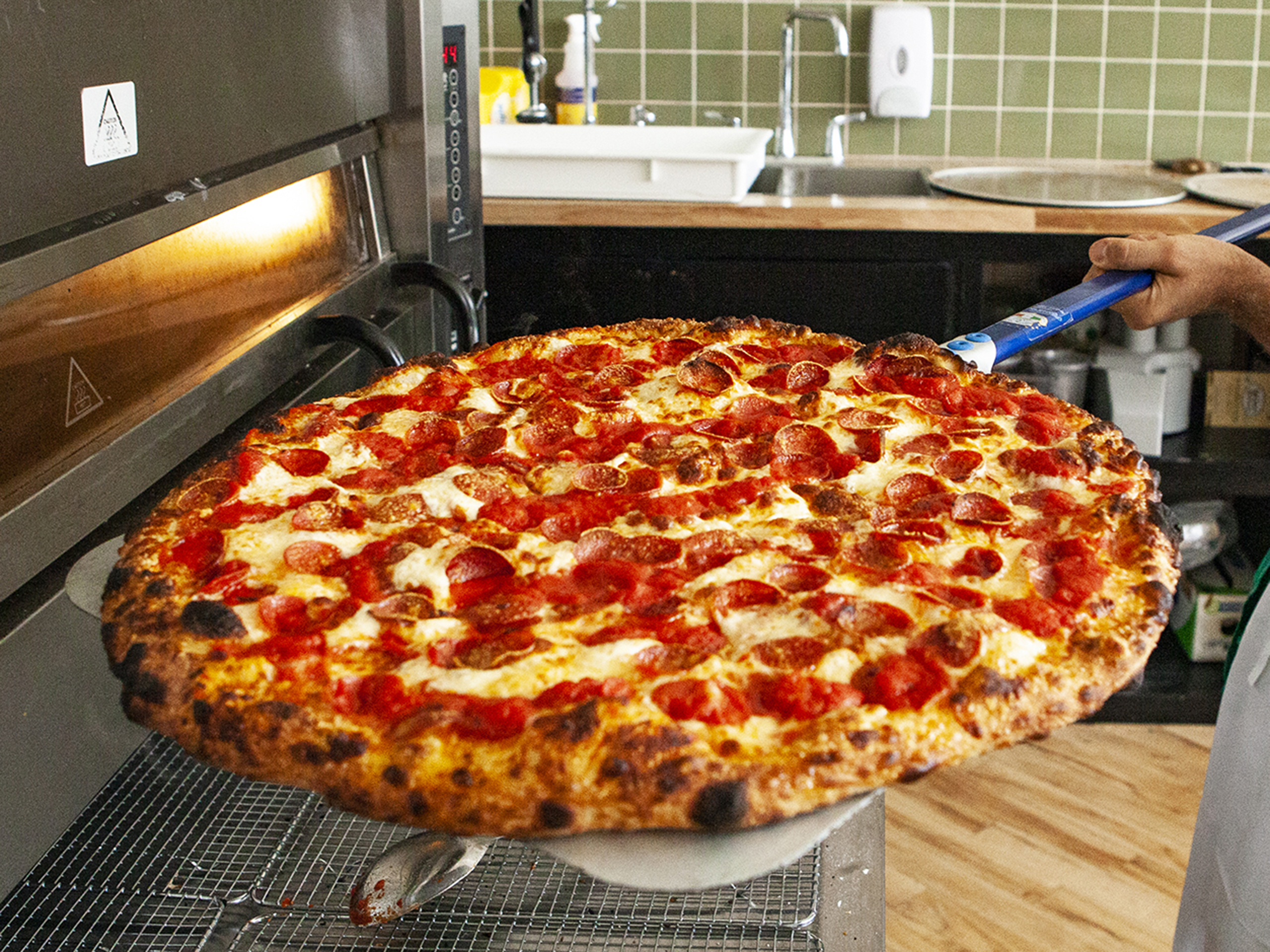 Pizzeria Badiali pepperoni pizza pie going into the pizza oven