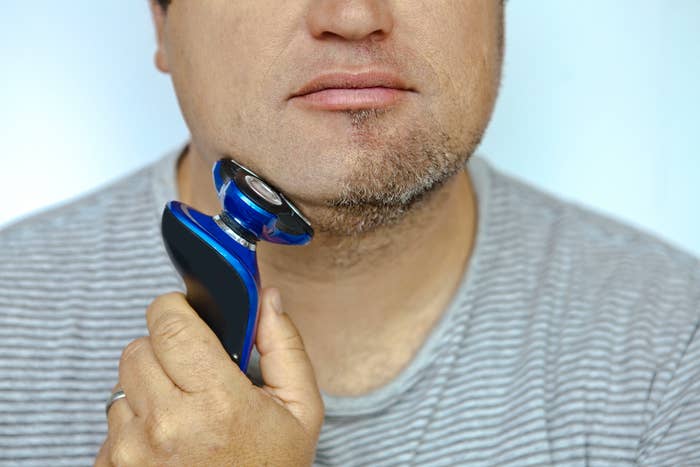 Man shaving using an electric razor.