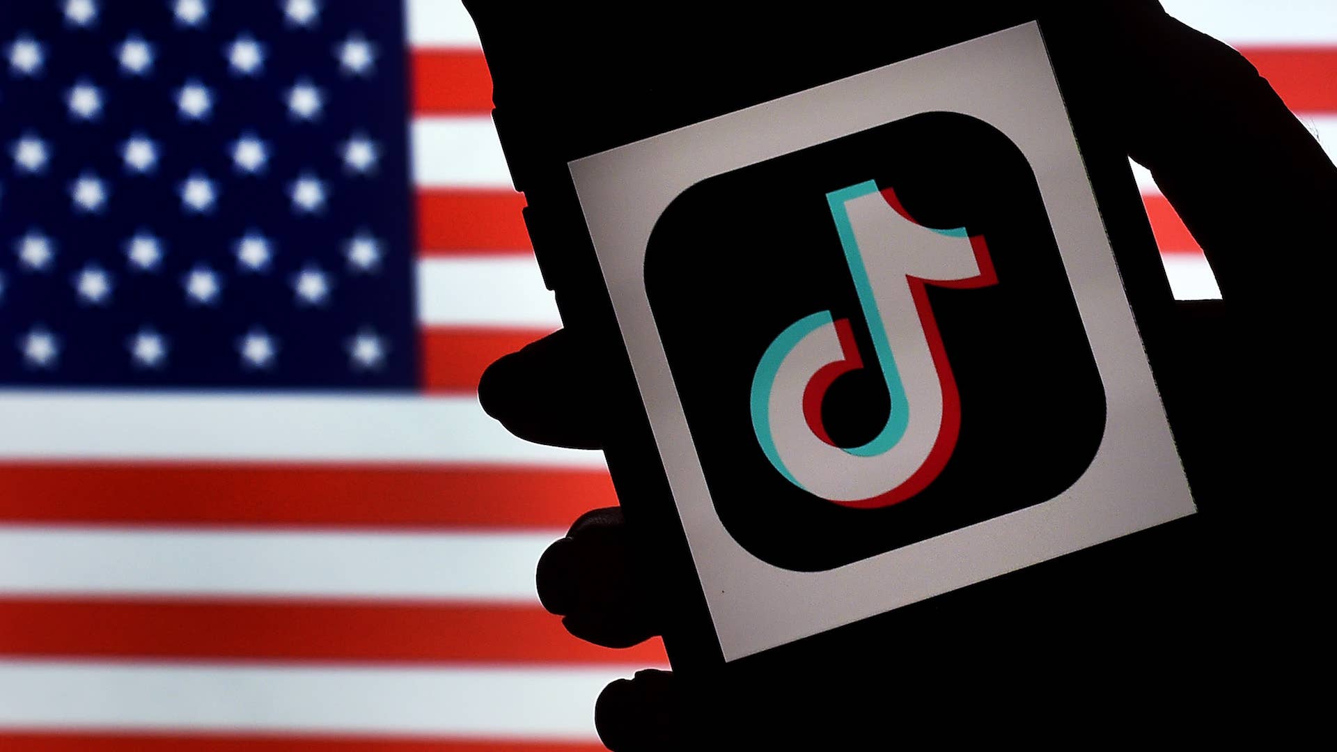 TikTok is displayed on the screen of an iPhone on an American flag background.