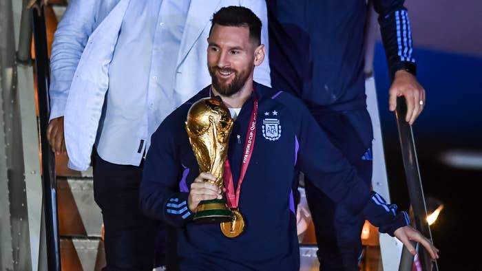 Messi holding a trophy while getting off the PJ