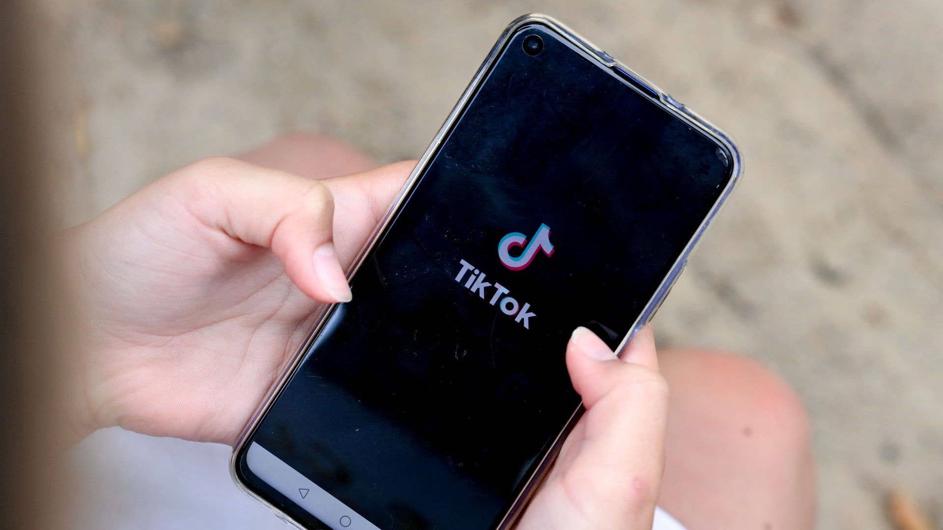 A girl is holding a smartphone in her hands with the logo of the short video app TikTok on it.