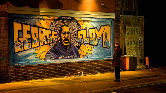 A person is seen looking at a George Floyd mural
