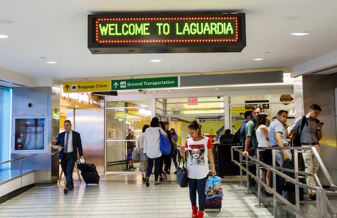 A man and woman with rolling luggage inside the LaGuardia Airport.