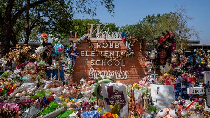 The Robb Elementary School sign is seen covered in flowers and gifts on June 17, 2022