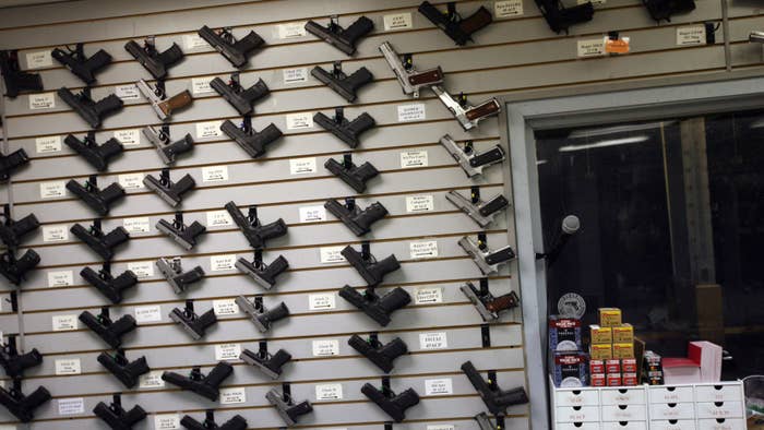 Hand guns hang on a display wall for sale.