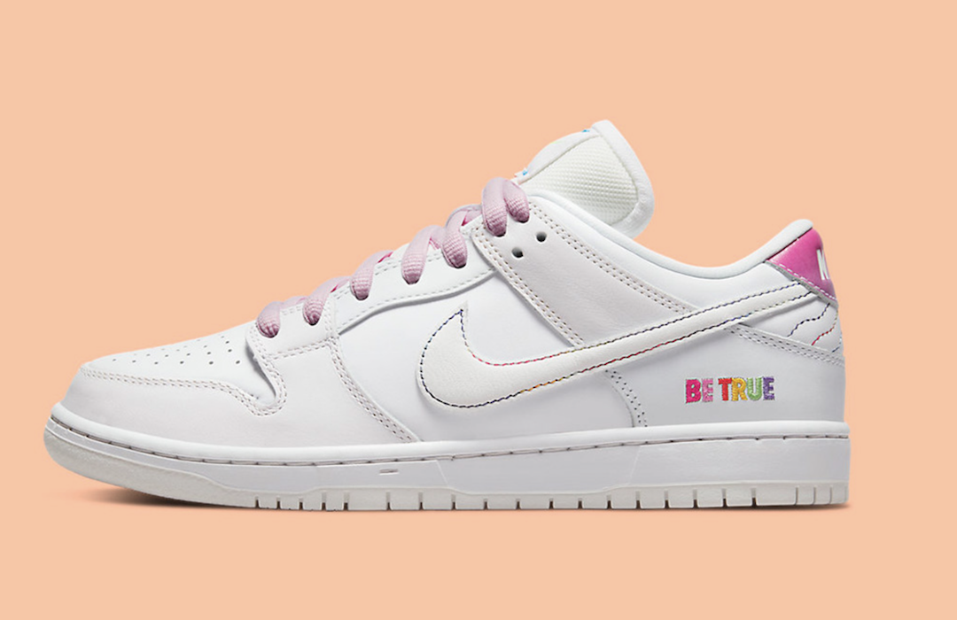A white Nike sneaker with pink laces and rainbow stitching