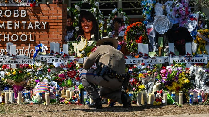 An officer pictured in front of makeshift memorial at Robb Elementary School.