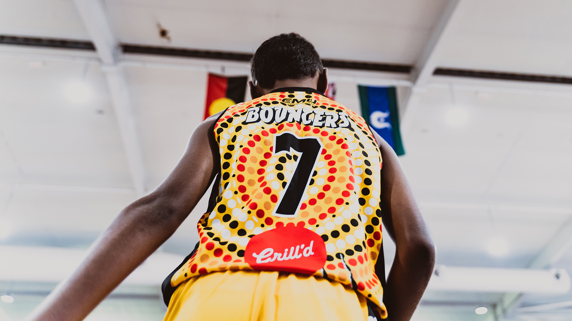 Basketball player in front of Australian Aboriginal and Torres Strait Island flags