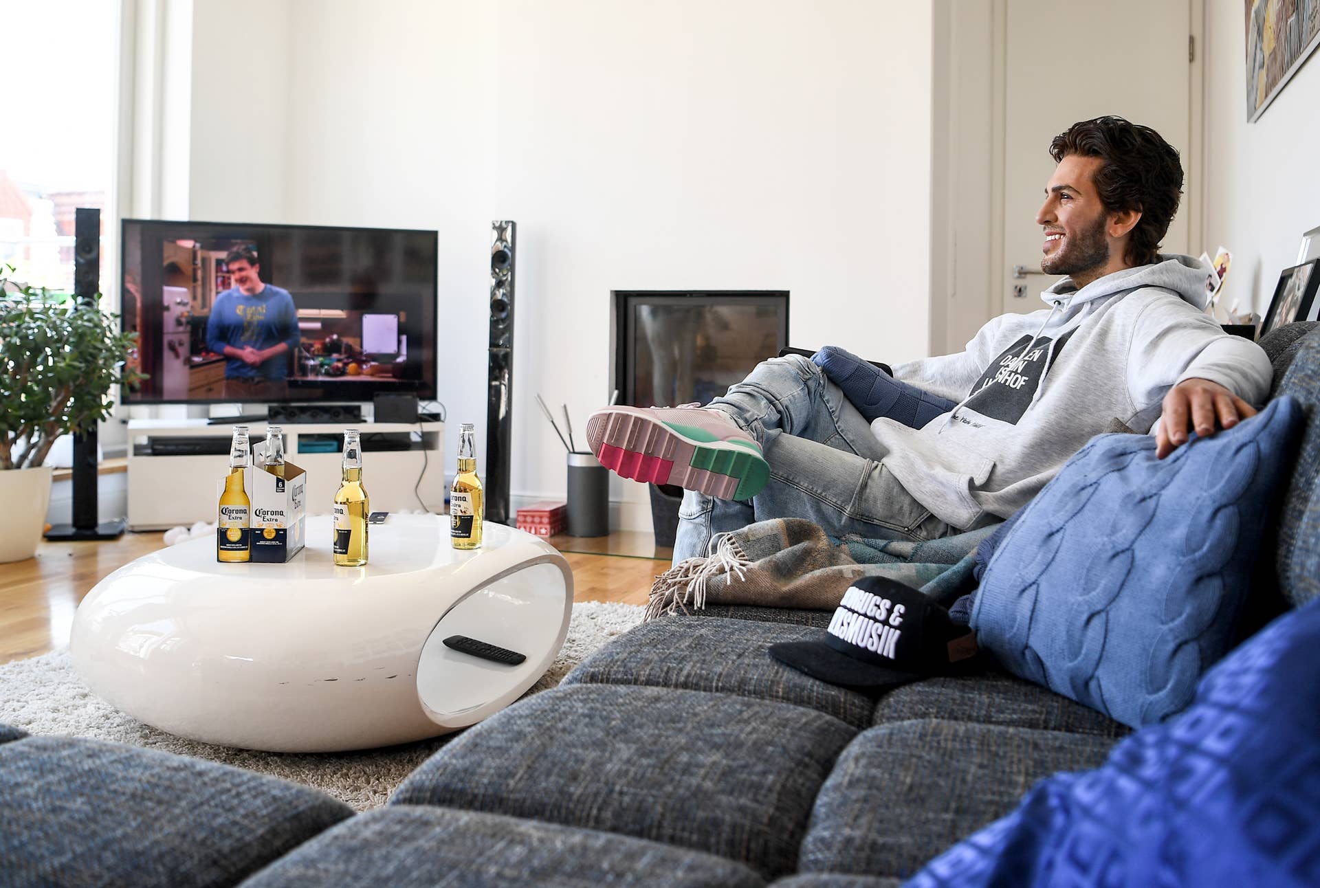 The wax figure of the actor Elyas M'Barek is shown in a scene on a couch while watching television