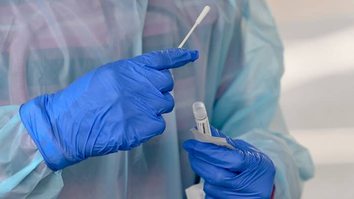 A nurse puts a swab into a vial after administering a test.
