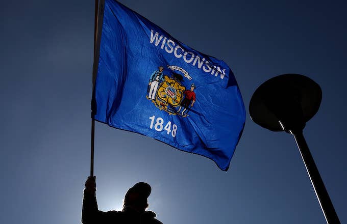 A demonstrator waves a Wisconsin flag in front of the Wisconsin State Capitol.