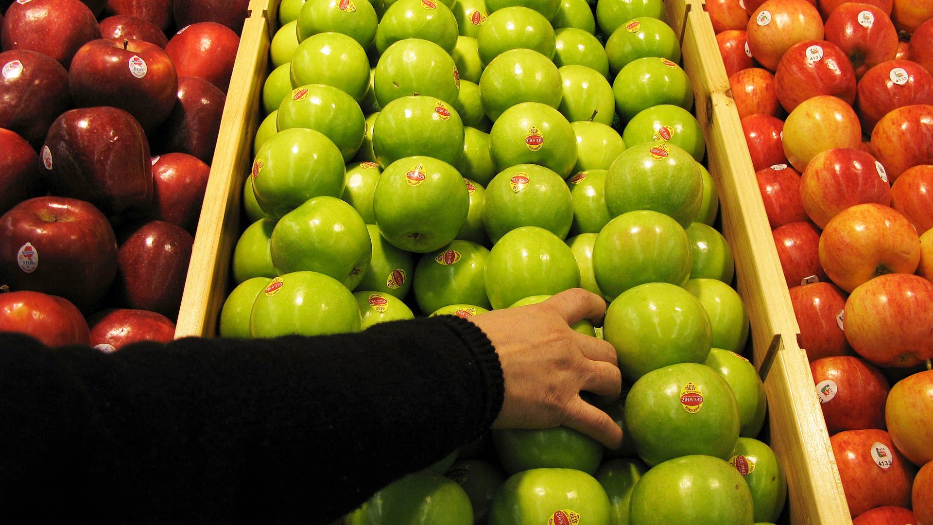 A shopper chooses granny smith apples at the newly-opened Tesco supermarket.
