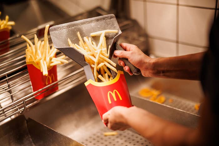 An employee fills carton with McDonald&#x27;s French fries.