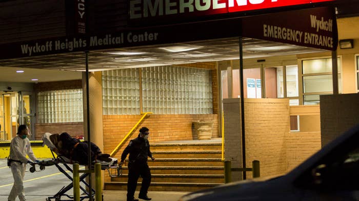 Two medical workers carry a patient on a stretcher in to Wyckoff Heights Medical Center