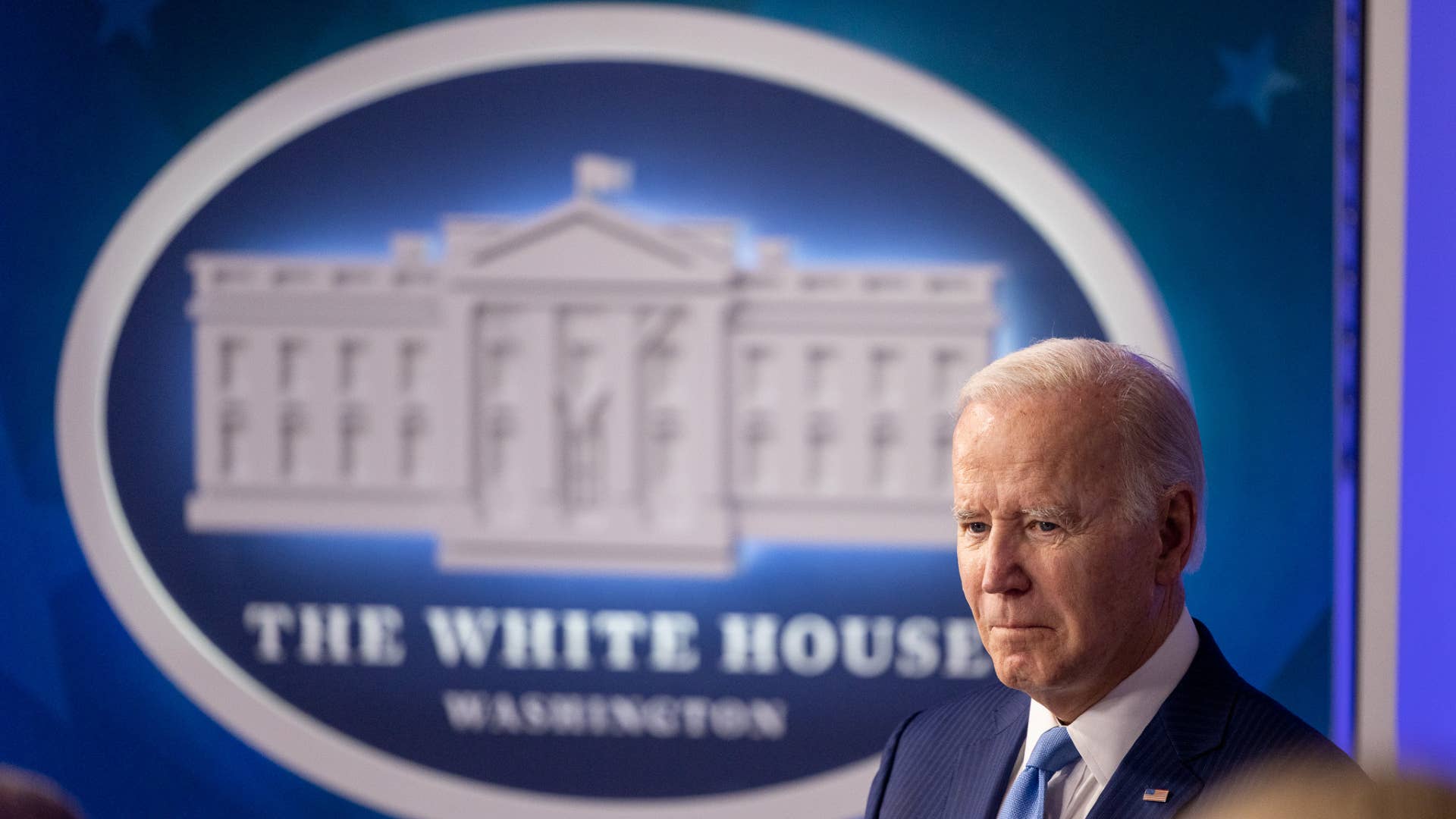 Biden is seen in front of a White House logo