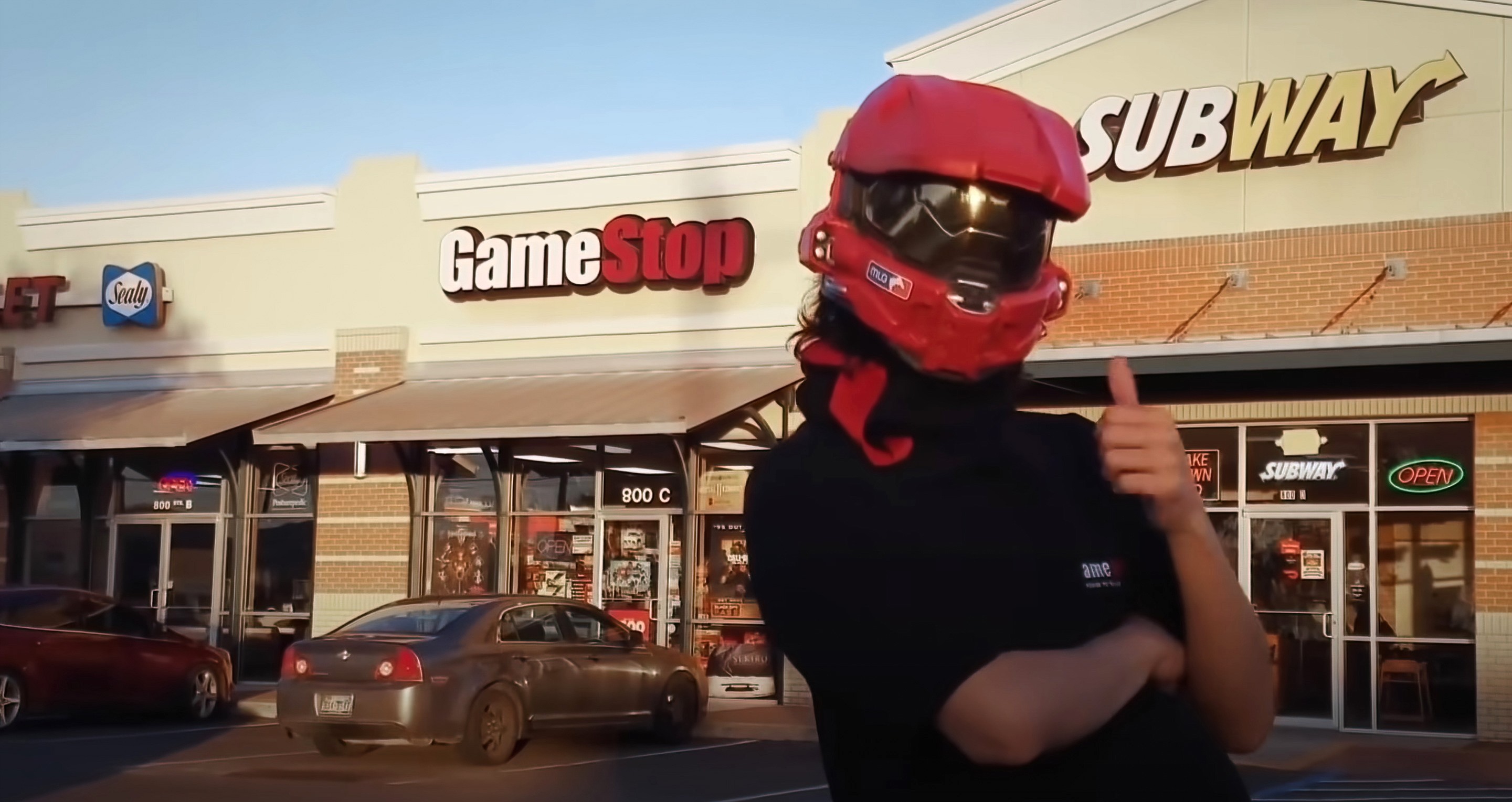 Gamestop with guy in front of it with a thumbs up sign