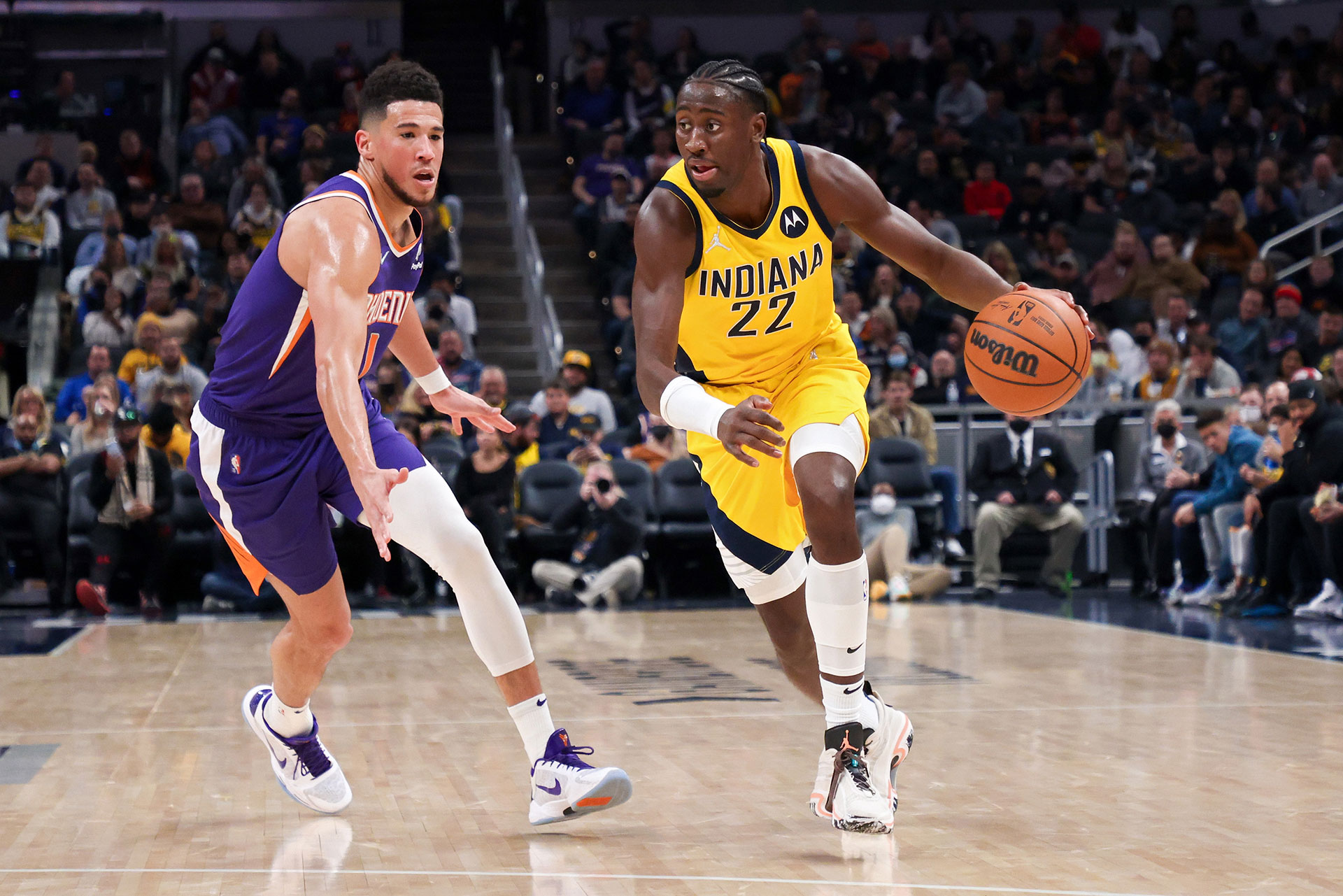 Caris LeVert #22 of the Indiana Pacers dribbles the ball while being guarded by Devin Booker #1
