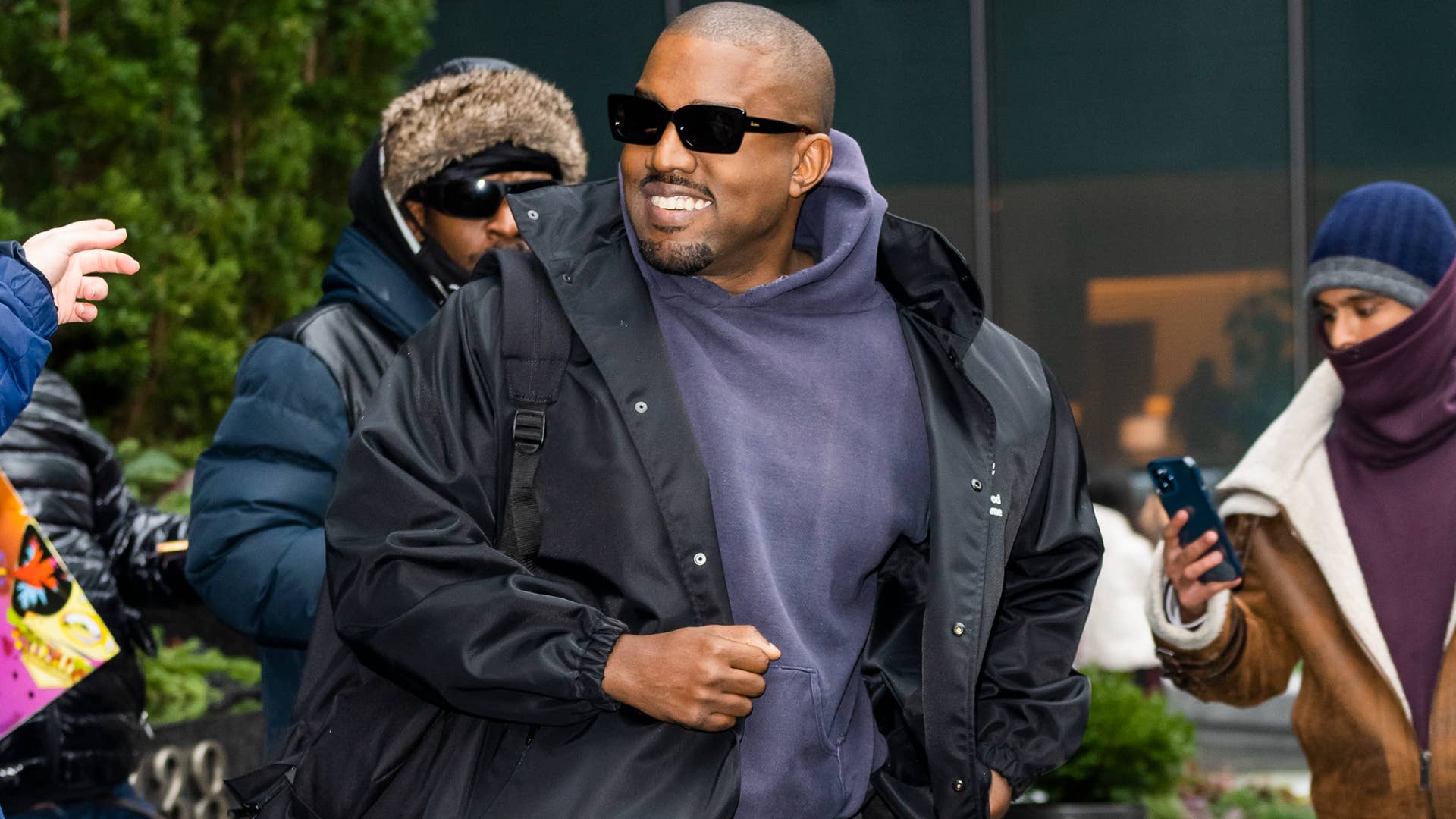 Ye is pictured smiling in front of photographers