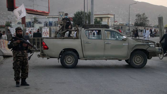 Taliban solider stands guard with truck