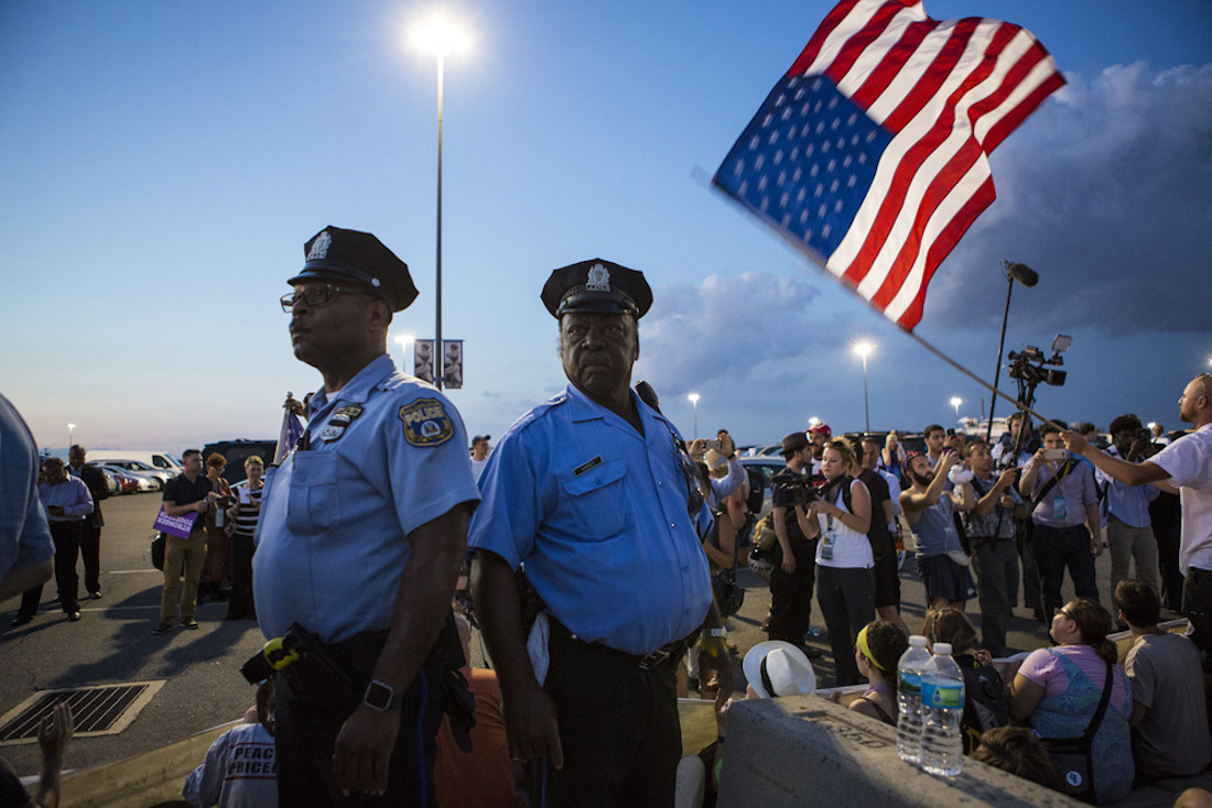 Police Officers stand beneath an American flag during a peaceful protest.
